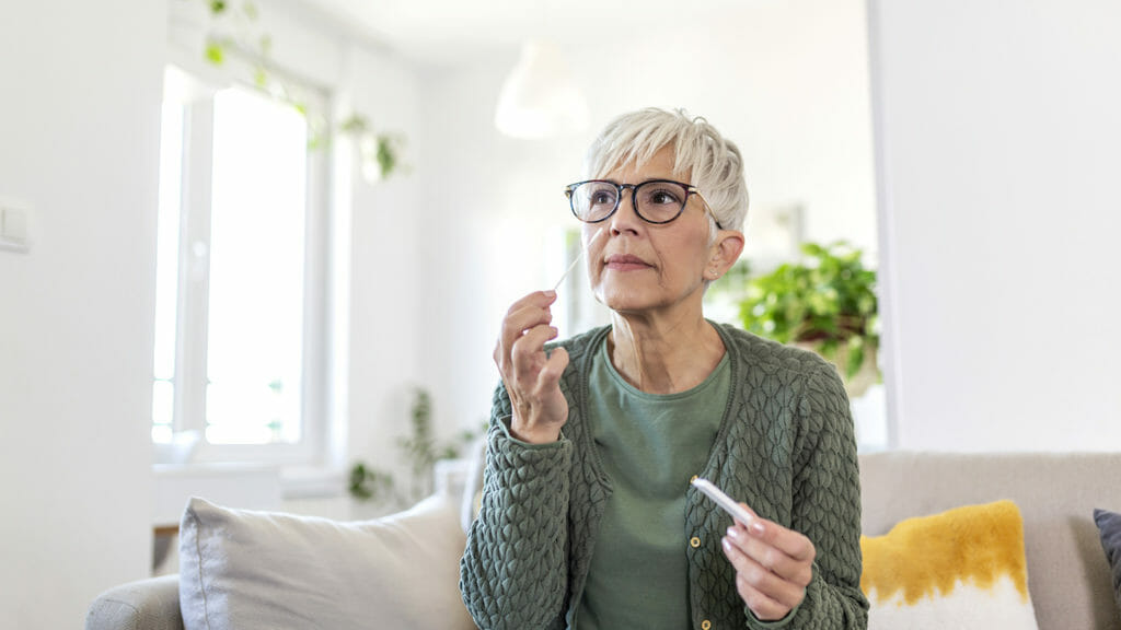 Portrait of relaxed mature woman taking a Self-swabbing home tests for COVID-19 at home.